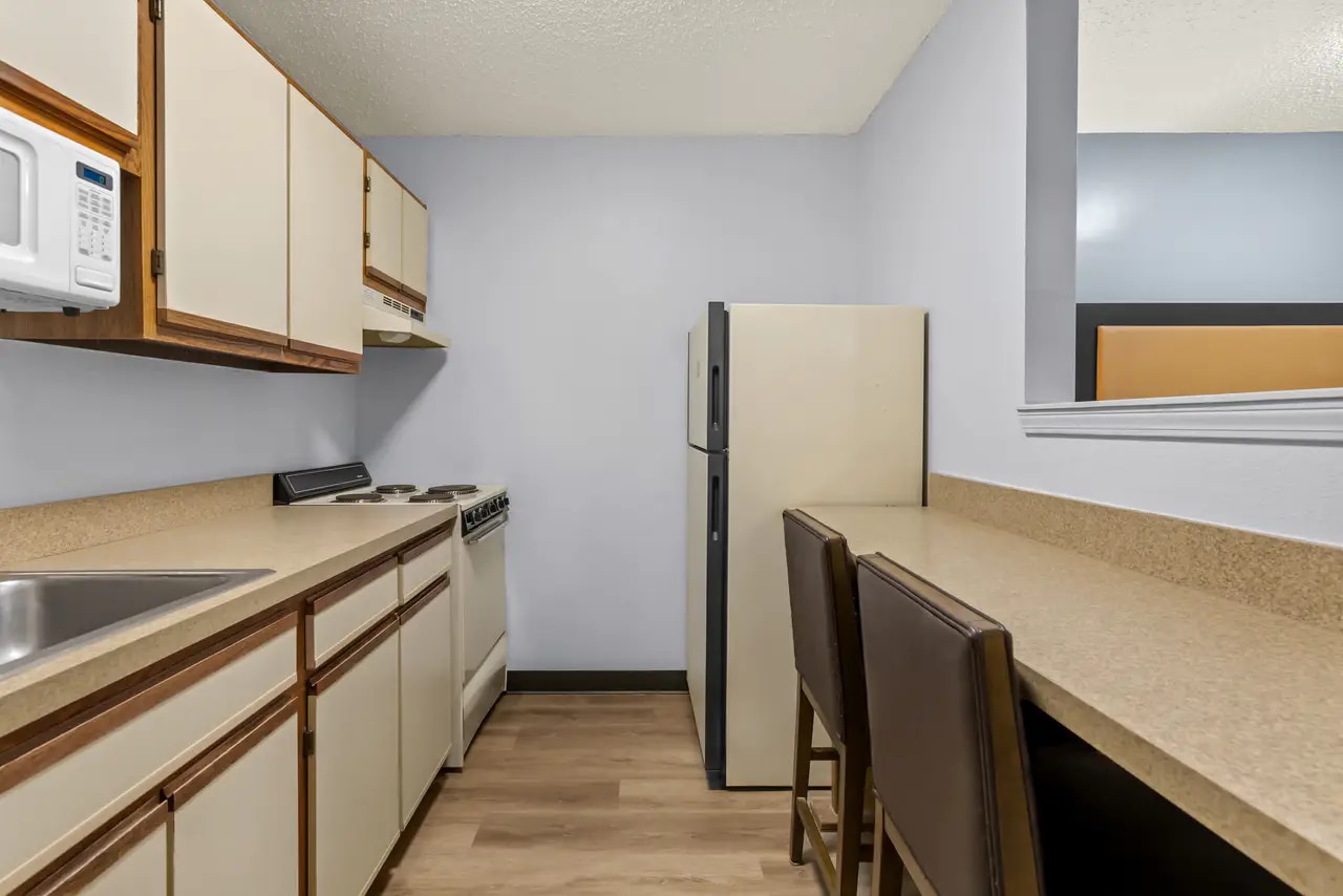 Guest room with queen bed, desk, television and kitchenette