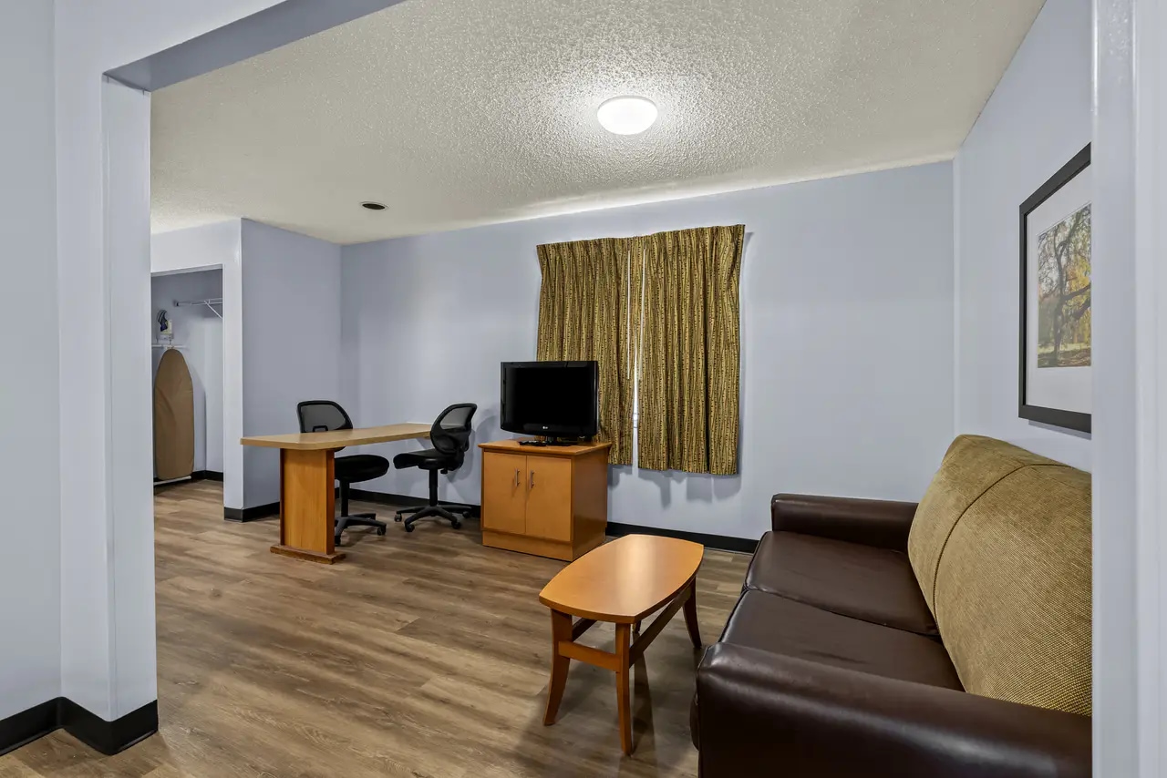 Extended-stay suite living area with sofa, work desk and television